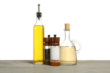 Salad dressings and spices on grey wooden table against white background