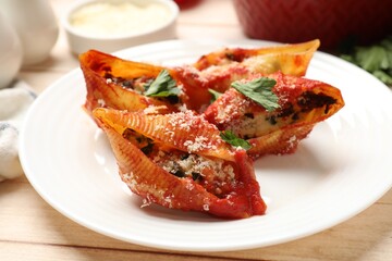 Delicious conchiglie pasta with ricotta cheese, tomato sauce and parsley on wooden table, closeup