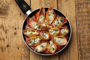 Delicious shell pasta stuffed with ricotta and spinach on wooden table, top view