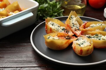 Delicious shell pasta stuffed with ricotta and spinach served on wooden table, closeup