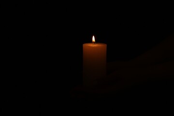 One burning church candle on dark background
