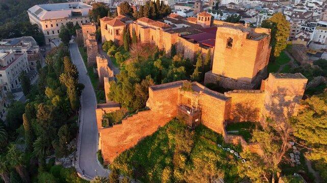 Malaga fortress in the morning golden light, aerial revealing shot, drone shot of Andalusian city of Malaga, tourism in Andalusia, Spain, Castillo de Gibralfaro in Malaga