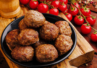 Delicious meatballs served on a black plate with cherry tomatoes