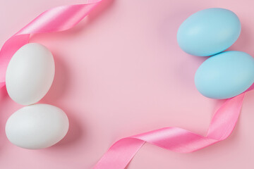 Happy Easter, pastel eggs and ribbon curly scroll on pink background.