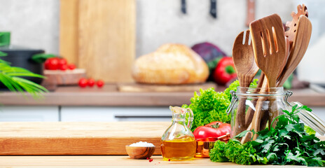 Healthy eating, cooking, food blogging background. Empty oak cutting board with tomatoes, lettuce, vegetables, olive oil on cozy kitchen with wooden table, kitchenware and ingredients