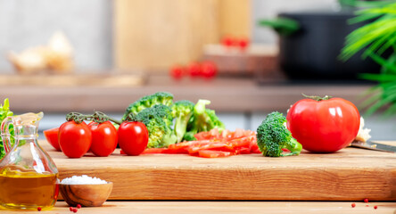 Healthy vegan  eating, cooking, food blogging background. Оak cutting board with broccoli, tomatoes on cozy kitchen with wooden table, kitchenware and spices