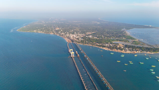 Scenic aerial image of the Pamban Bridge at sunrise, as the golden hues reflect over the serene waters, making it a picturesque sight.