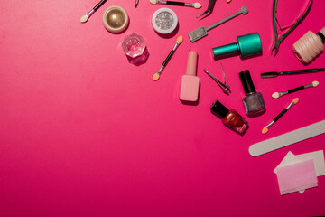 Various nail art tools and accessories are arranged on a vibrant pink background. Brushes,...