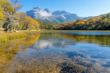Fototapeta premium Autumn Lake Reflection Of Snow Capped Mountains Under Blue Sky