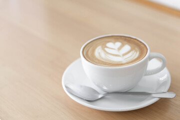 A beautifully crafted latte art in a white ceramic cup, featuring delicate leaf latte art on its creamy surface. 