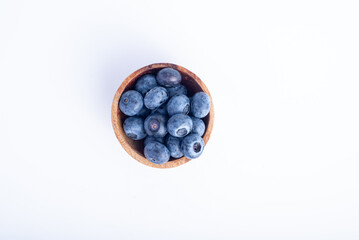 Close-up of fresh blueberries in a rustic wooden bowl, isolated on a clean white background. The vibrant berries highlight their natural texture, perfect for breakfast, desserts, and healthy snacks