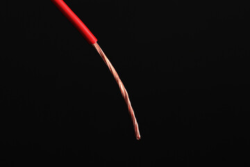 Red stripped electrical wire on black background, closeup