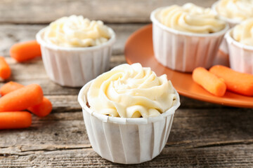 Delicious carrot muffins and fresh vegetables on wooden table, closeup