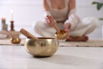 Woman with singing bowls on floor indoors, selective focus