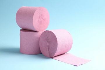Pink toilet paper rolls on light blue background