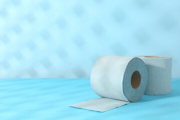 Light blue toilet paper rolls on color background, space for text