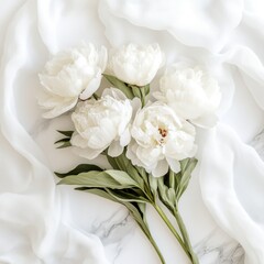 A bouquet of white flowers sits atop a clean white sheet, perfect for still life or decorative uses