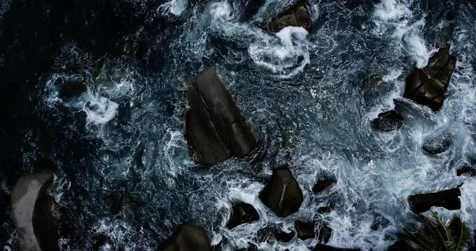 Aerial top angle view sea wave rolling foamy on rock beach
