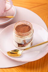 Delicious chocolate dessert served in a glass jar on a pink plate with a golden spoon, showcasing a delightful treat for sweet lovers, dessert concept