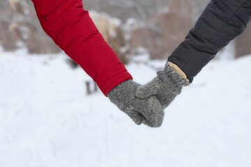 Couple holding hands in winter forest on a walk.A man and a woman in identical mittens holding hands.The concept of love and family.