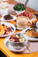 Delicious breakfast spread featuring fresh fruits, pastries, coffee, and desserts on a wooden table, showcasing a vibrant morning meal experience, healthy eating concept