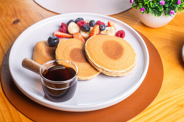 Delicious fluffy pancakes served with fresh berries and maple syrup on a white plate, perfect for breakfast or brunch, healthy eating concept