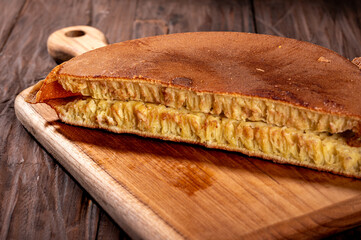 A thick Indonesian martabak with a golden brown crust and fluffy texture sits on a wooden board....