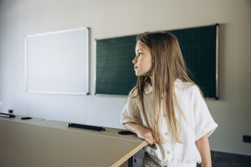 Young girl in classroom leaning on desk