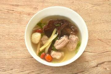 boiled day lily topping tofu with pork bone and ear mushroom in Chinese herb soup on bowl 
