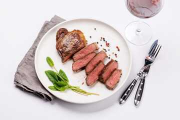 A perfectly cooked sliced striploin steak with a juicy, tender texture, served alongside a glass of rich red wine