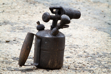 There is an old blowtorch on the concrete floor