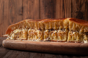 A sliced Indonesian martabak with a golden brown crust sits on a wooden board. Filled with grated cheese, chocolate sprinkles, and peanuts, against the rustic wooden background