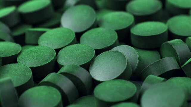 Chlorella or spirulina algae green powder pills circle rotation close up. Dietary supplement to improve health. Seaweed superfood. Healthy food background. Vitamins and minerals to diet detox