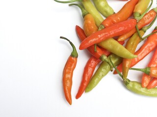 Natural image of several light green, orange and red chilies ready to be processed into spicy cooking spices with a white isolated background