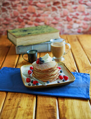 stack of pancakes topped with fresh fruit and whipped cream