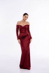 Beautiful tender brunette girl in a burgundy evening luxury dress isolated on a white background