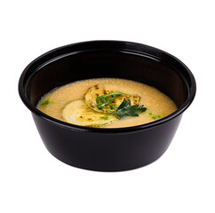 A black bowl of soup and vegetables on a white background