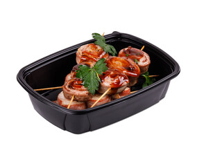 A black plastic container that is filled with meat on skewers inside