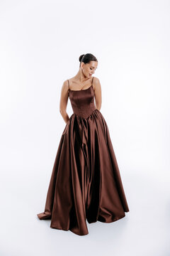 Tall brunette with hairstyle in dark brown luxurious fashionable dress with train isolated on white background