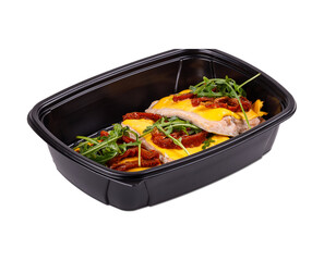 A black plastic container brimming with assorted food on a white background