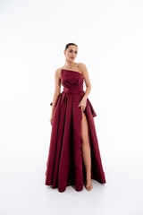 Fototapeta premium Sexy brunette girl in a burgundy long dress with a bow on the back