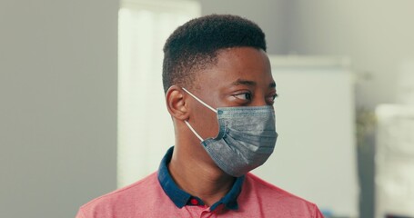 Portrait of a young man with dark eyes hair black skin on face protective mask man is wearing salmon collar shirt student in classroom is looking at window and then at camera