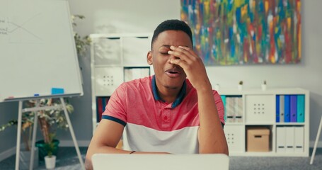 Fototapeta premium Handsome man working for large company sits in office in front of laptop talks to co-worker on video conference webcam they discuss about project guy breaks down amount of work gestures he will call