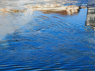 Reflections in a serene water surface during a bright day near a quaint village