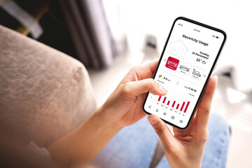 Young woman monitoring home electricity usage with mobile apps. Eco-friendly technologies and practices concept