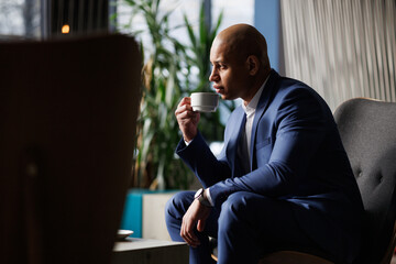 Elegant african american businessman drinking coffee in hotel lobby