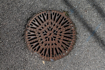 Rusty Manhole Cover on Asphalt