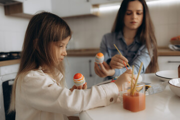 Mother and Daughter Painting Colorful Easter Eggs at a Kitchen Table