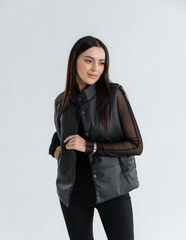 Portrait of a cute girl model in a black vest and pants on a white background in the studio