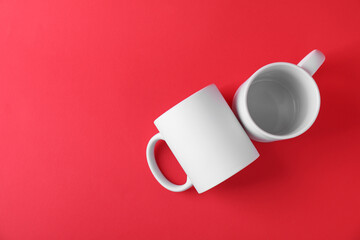 Two blank white mugs on red background, top view. Mockup for design